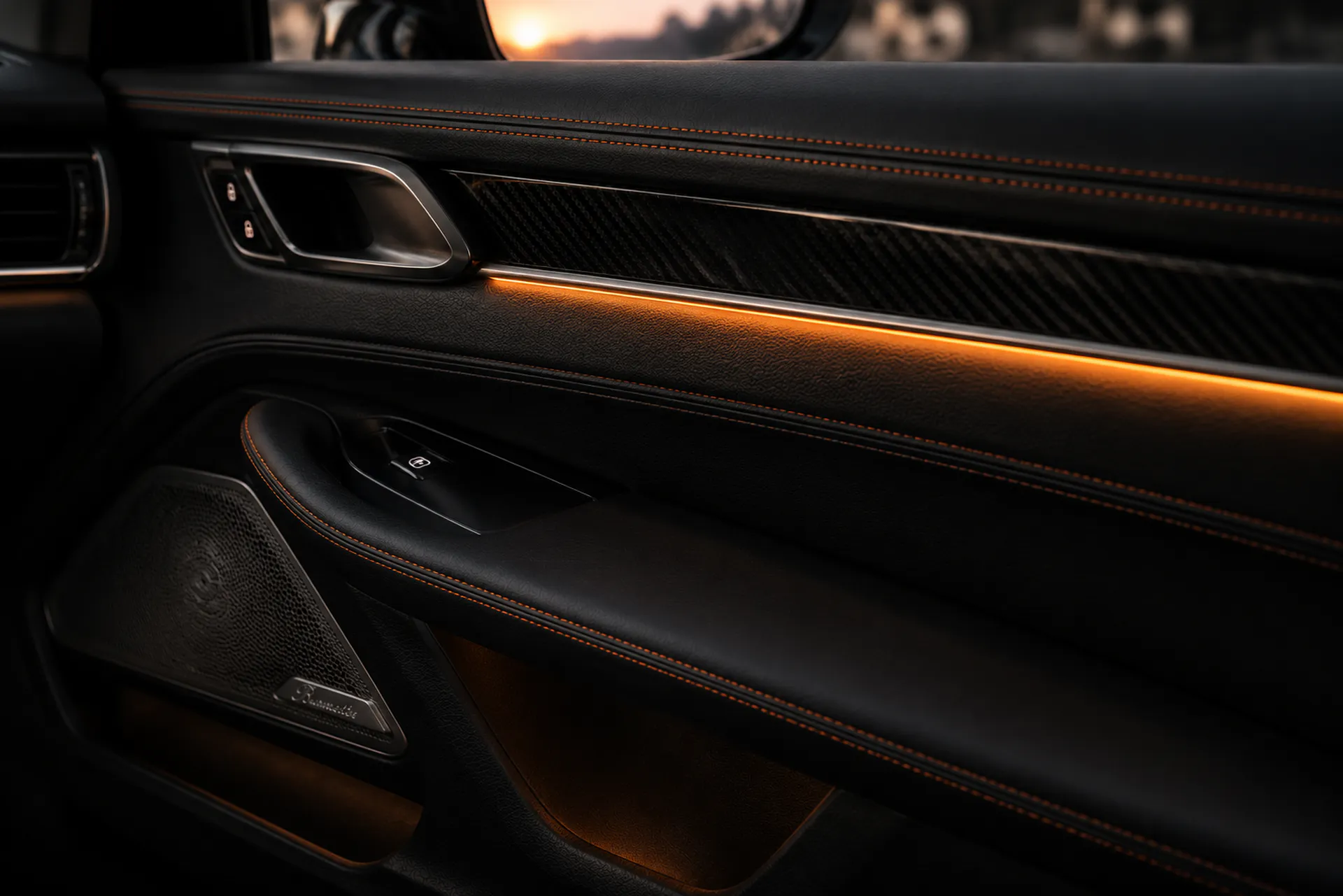 Bespoke Porsche interior door panel with black leather, satin carbon and orange ambient lighting